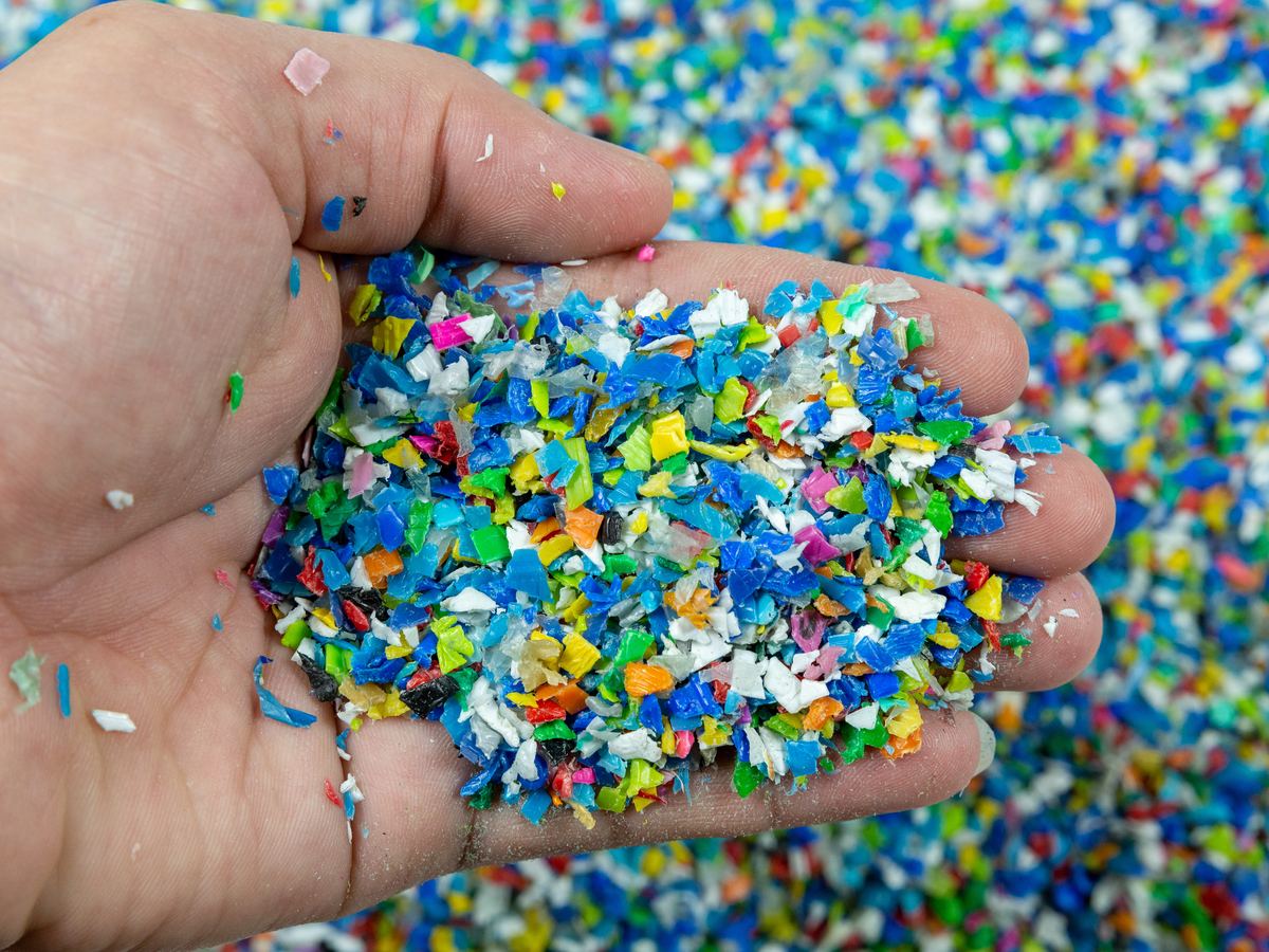 Una mano che tiene del macinato plastico di colori diversi